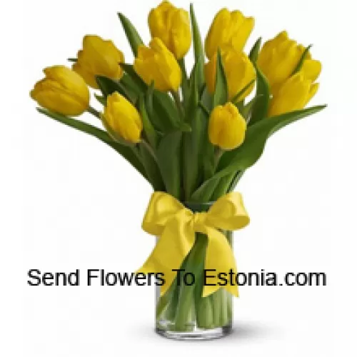 Gelbe Tulpen mit saisonalen Füllstoffen und Blättern in einer Glasvase - Bitte beachten Sie, dass bei Nichtverfügbarkeit bestimmter saisonaler Blumen diese durch andere Blumen mit gleichem Wert ersetzt werden.