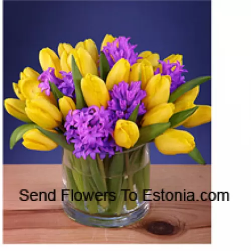 Желтые тюльпаны красиво оформлены в стеклянной вазе - обратите внимание, что в случае отсутствия определенных сезонных цветов их можно заменить другими цветами того же стоимости