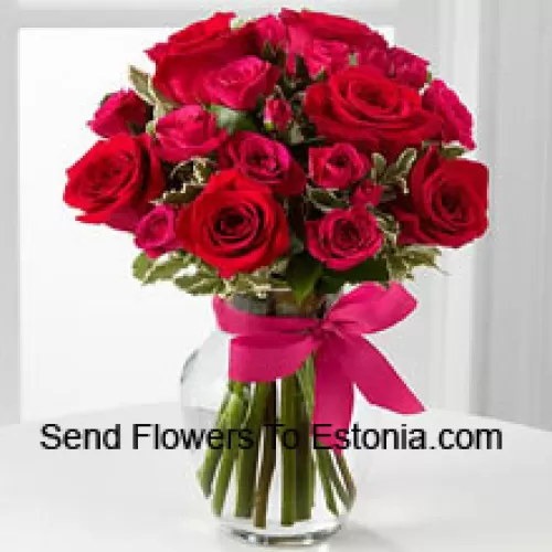19朵红玫瑰，搭配季节性的插花，装在玻璃花瓶中，配有粉红色蝴蝶结装饰