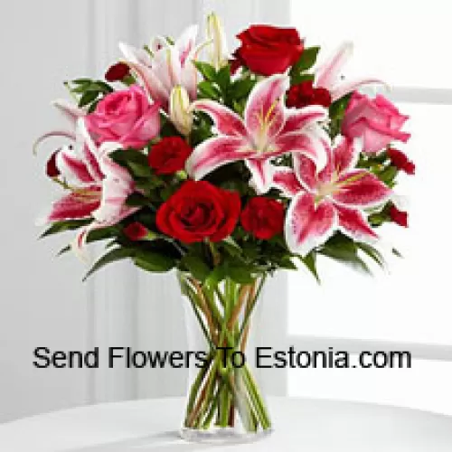 유리 꽃병에 담긴 빨간색과 분홍색 장미와 분홍색 릴리와 계절적인 채움재료