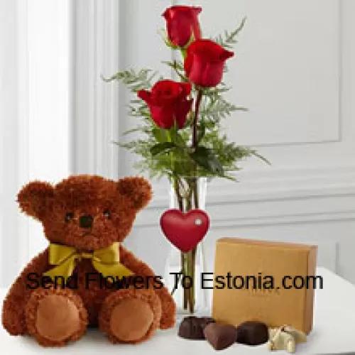 Trei trandafiri roșii cu frunze verzi într-un vas, un ursuleț de pluș maro drăguț de 10 inch și o cutie de ciocolată Godiva. (Ne rezervăm dreptul de a înlocui ciocolata Godiva cu ciocolată de valoare egală în caz deindisponibilitate. Stoc limitat)